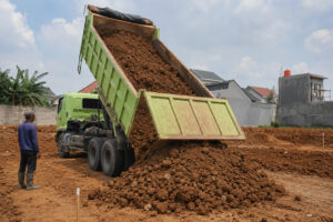 Proses dump truck menurunkan tanah urug di lokasi proyek